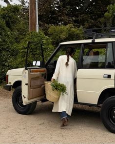 a woman with a basket is standing next to a white suv that has it's door open