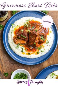 two blue plates topped with meat and mashed potatoes on top of a wooden table