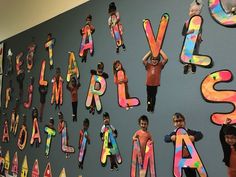 children standing in front of a wall with letters and numbers on it