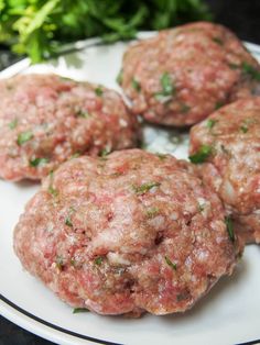 four meatballs on a plate with parsley