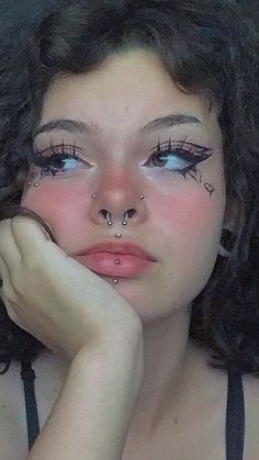 a woman with fake eyelashes and piercings on her nose is looking at the camera