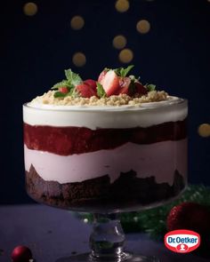 a layered cake with strawberries and crumbs on top is sitting on a table