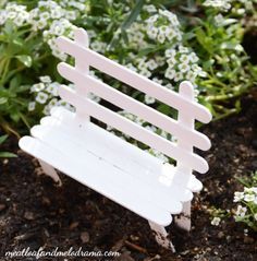 a miniature white bench sitting in the dirt