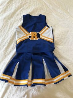 a blue and white cheerleader dress laying on top of a bed