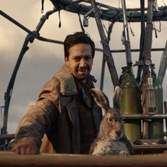 a man standing next to a rabbit on top of a wooden structure with lots of wires