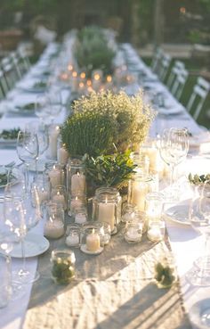 a long table is set with candles and greenery