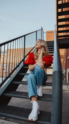 a woman is sitting on the stairs and looking up