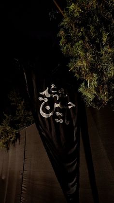 a black banner hanging from the side of a tree