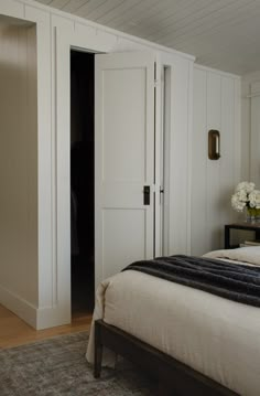 a bed sitting in a bedroom next to a white closet with doors on each side