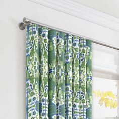 green and blue curtains hanging on the side of a white wall next to a window