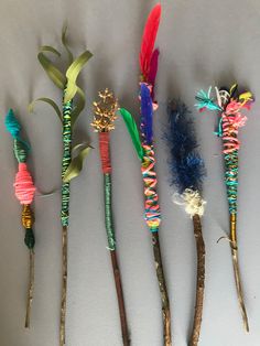 five different colored feathers are on sticks