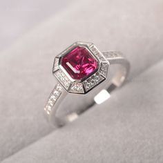 a close up of a ring with a pink stone in the center and white diamonds around it