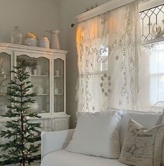 a living room filled with furniture and a christmas tree in front of a window sill