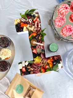 a table topped with cakes and cupcakes on top of a white table cloth