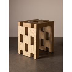 a small wooden block sitting on top of a cement floor in front of a wall