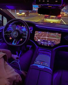 the interior of a car with blue lights and electronic devices on the dash board, along with other vehicles