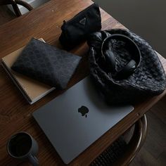 an apple laptop computer sitting on top of a wooden table next to a black purse