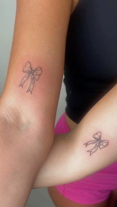 two women with tattoos on their arms, one has a bow and the other has a heart