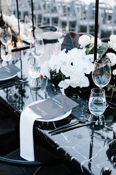 the table is set with white flowers and wine glasses