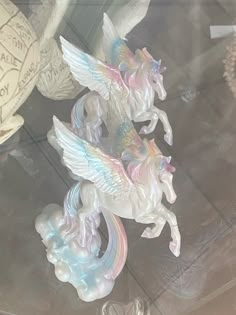 three plastic unicorn figurines sitting on top of a glass table