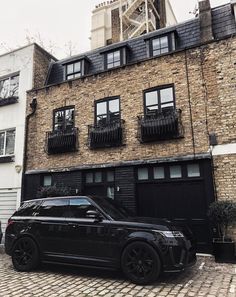 a black car parked in front of a brick building with balconies on the windows