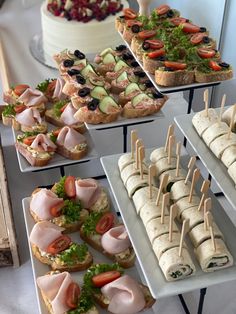 an assortment of appetizers and sandwiches displayed on serving trays with toothpicks