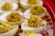 deviled eggs on a red and white checkered plate with mustard sprinkled on them