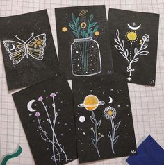 four black cards with drawings of flowers and plants in them on a sheet of paper