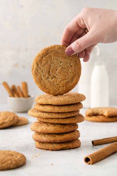 a stack of cookies being stacked on top of each other with cinnamon sticks in the background