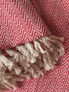 a red and white blanket with fringes on it's edges, laying down