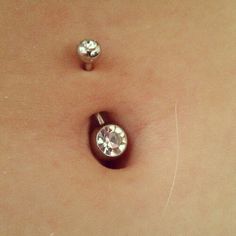 two piercings on the side of a woman's stomach, one with a diamond in it