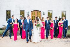 a bride and groom with their bridal party in front of a white brick building