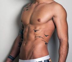 a man with tattoos on his chest standing next to a wall