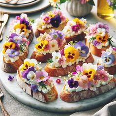 small sandwiches with flowers on them sitting on a plate next to silverware and utensils