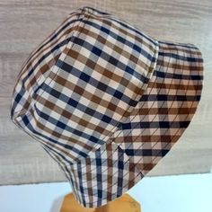 a brown and white checkered hat on a wooden stand