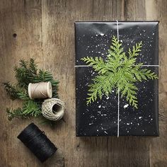 a present wrapped in black paper with a green tree on it next to twine of twine