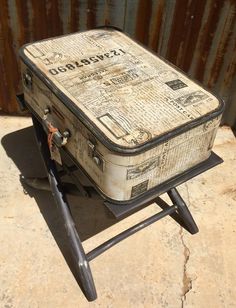 an old suitcase sitting on top of a metal stand next to a rusted wall