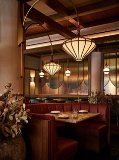 a restaurant with red booths and wooden tables in the center, along with hanging lights