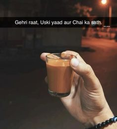 a hand holding a glass filled with liquid in front of a dark background and the words gehri raat, uski yaad aur chai kaa ka sath