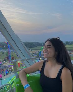 a woman sitting on top of a green chair at an amusement park