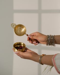 two women are holding small bowls and spoons in their hands, while one holds a tea strainer