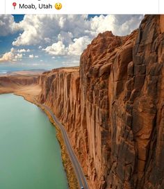 an aerial view of a road going through the mountains next to a body of water