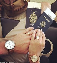 a person holding two passports in their hands while sitting on a couch next to a bag