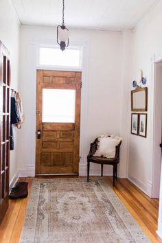 a wooden door in a white room next to a chair