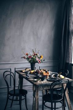 a wooden table topped with plates of food next to a vase filled with flowers on top of a window sill