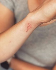 a woman with a small red heart tattoo on her arm