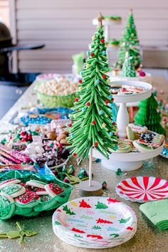 a table topped with lots of plates and christmas tree shaped decorations on top of it