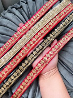 three red and gold headbands are held in the palm of someone's hand