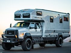 a truck with a camper attached to it's bed is parked in front of a mountain