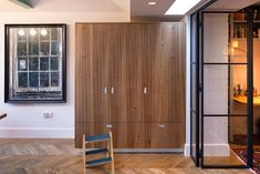 an empty chair in front of a wooden cabinet and glass doored entry way to a home office